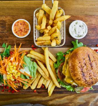 Burger mit Salat und Pommes auf Holzbrett