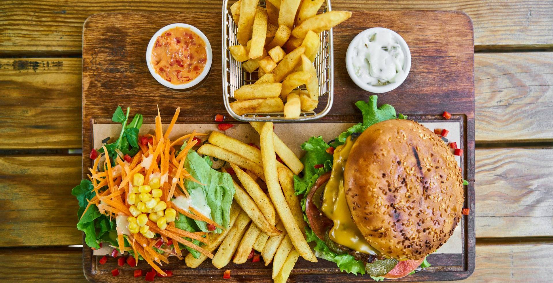 Burger mit Salat und Pommes auf Holzbrett